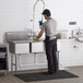 A man washing a Regency 3 compartment sink with a faucet.