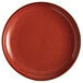 An Acopa Keystone Sedona Orange stoneware coupe plate with speckled specks.