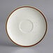 A white saucer with brown specks on the rim.