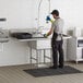 A man in a kitchen cleaning a Regency stainless steel commercial sink with drainboards.