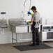 A man washing a Regency stainless steel two compartment sink.