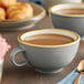 Two Acopa Keystone granite gray stoneware cups of coffee on a table with a spoon and fork.