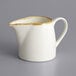 A white stoneware creamer with a white handle and brown accents.