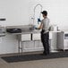 A man wearing an apron washing a Regency 3 compartment commercial sink.