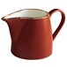 A red pitcher with a white handle.