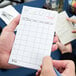 A person holding a white Choice 1 Part Waiter Order Pad with a pen.