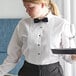 A woman in a white Henry Segal tuxedo shirt holding a tray with a wine glass.