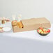 A woman using a Sabert extra large catering tray to serve bagels and apples.