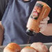 A woman pours McCormick Grill Mates Smokehouse Maple Seasoning on chicken.