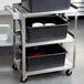 A Vollrath stainless steel utility cart with three black containers on it.