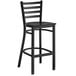 A Lancaster Table & Seating black metal ladder back bar stool with black wood seat.