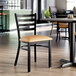 A ladder back chair with a distressed copper finish and a light brown vinyl padded seat.