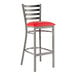 A Lancaster Table & Seating ladder back bar stool with a red vinyl cushion on a gray surface.
