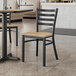 A Lancaster Table & Seating Black Ladder Back Chair with Driftwood Seat on a table in a restaurant.