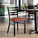 A ladder back chair with a distressed copper finish and a 2 1/2-inch burgundy vinyl padded seat.