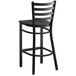 A black metal Lancaster Table & Seating ladder back bar stool with a black wood seat.