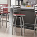 A group of Lancaster Table & Seating bar stools with mahogany seats at a counter in a restaurant.