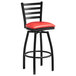 A Lancaster Table & Seating black ladder back swivel bar stool with a red cushion.