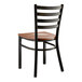 A Lancaster Table & Seating black metal ladder back chair with a wood seat.