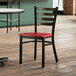 A Lancaster Table & Seating distressed copper ladder back chair with a mahogany seat on a wooden floor.