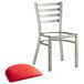 A silver metal Lancaster Table & Seating ladder back chair with a red vinyl cushion