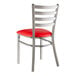A Lancaster Table & Seating metal ladder back chair with a red vinyl seat