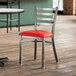 A Lancaster Table & Seating ladder back chair with a red vinyl padded seat on a table in a restaurant.
