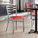 A Lancaster Table & Seating clear coat finish ladder back chair with a red vinyl padded seat on a table in a restaurant