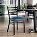 A ladder back chair with a distressed copper finish and a navy vinyl padded seat.