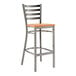 A Lancaster Table & Seating metal ladder back bar stool with a cherry wood seat.