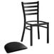 A Lancaster Table & Seating black metal ladder back chair with black vinyl pad.