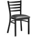 A Lancaster Table & Seating black metal ladder back chair with a black vinyl cushion.