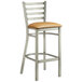 A Lancaster Table & Seating metal bar stool with a light brown vinyl cushion.