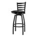 A black metal ladder back swivel bar stool with a black vinyl padded seat and circular footrest.