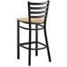 A Lancaster Table & Seating black ladder back bar stool with a natural wood seat.