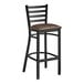 A Lancaster Table & Seating black ladder back bar stool with dark brown vinyl padded seat.