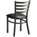 A Lancaster Table & Seating black metal ladder back chair with a black cushion.