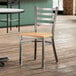 A Lancaster Table & Seating wooden chair with a clear coat finish ladder back and natural wood seat.