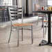 A Lancaster Table & Seating ladder back chair with a natural wood seat at a table in a restaurant.