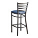A Lancaster Table & Seating metal ladder back bar stool with a navy blue vinyl padded seat.