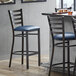 A Lancaster Table & Seating ladder back bar stool with a navy blue vinyl padded seat.