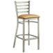 A Lancaster Table & Seating metal ladder back bar stool with a light brown cushion.