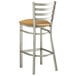 A Lancaster Table & Seating metal ladder back bar stool with a light brown vinyl cushion.