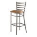 A Lancaster Table & Seating metal bar stool with a light brown vinyl padded seat.