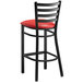 A Lancaster Table & Seating black ladder back bar stool with a red vinyl padded seat.