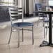 A Lancaster Table & Seating ladder back chair with a detached navy vinyl padded seat.