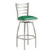 A Lancaster Table & Seating clear coat finish swivel bar stool with a green vinyl cushion.