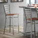 A Lancaster Table & Seating bar stool with a wooden ladder back and brown wood seat.