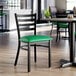 A black ladder back chair with a green vinyl padded seat.
