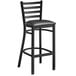 A Lancaster Table & Seating black metal ladder back bar stool with black vinyl cushion.